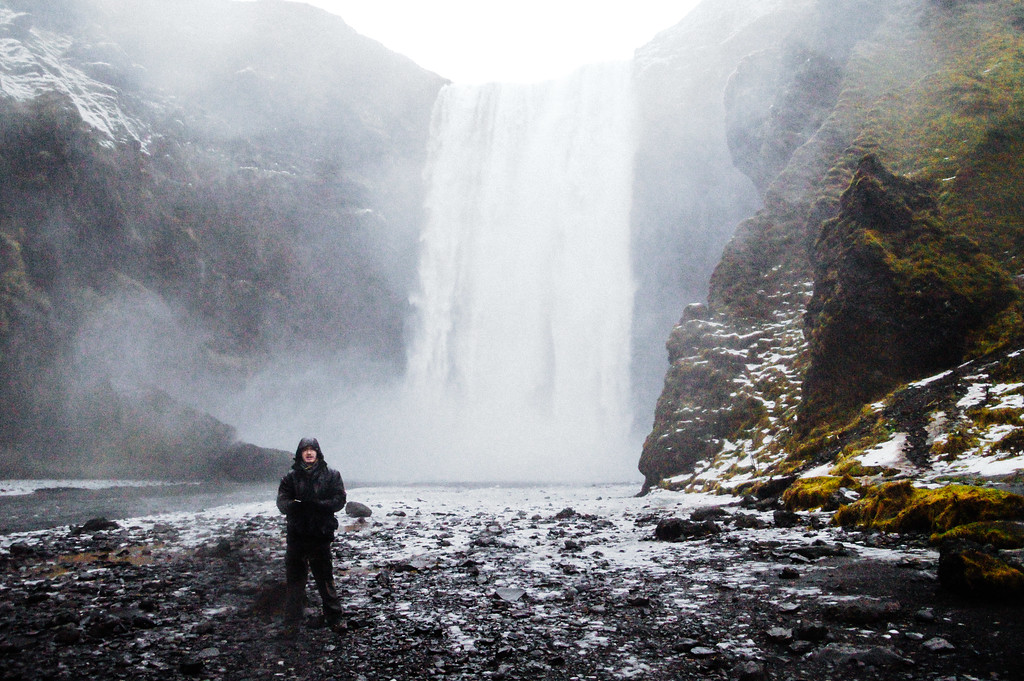 Gary in a raincoat in front of Skógafoss waterfall