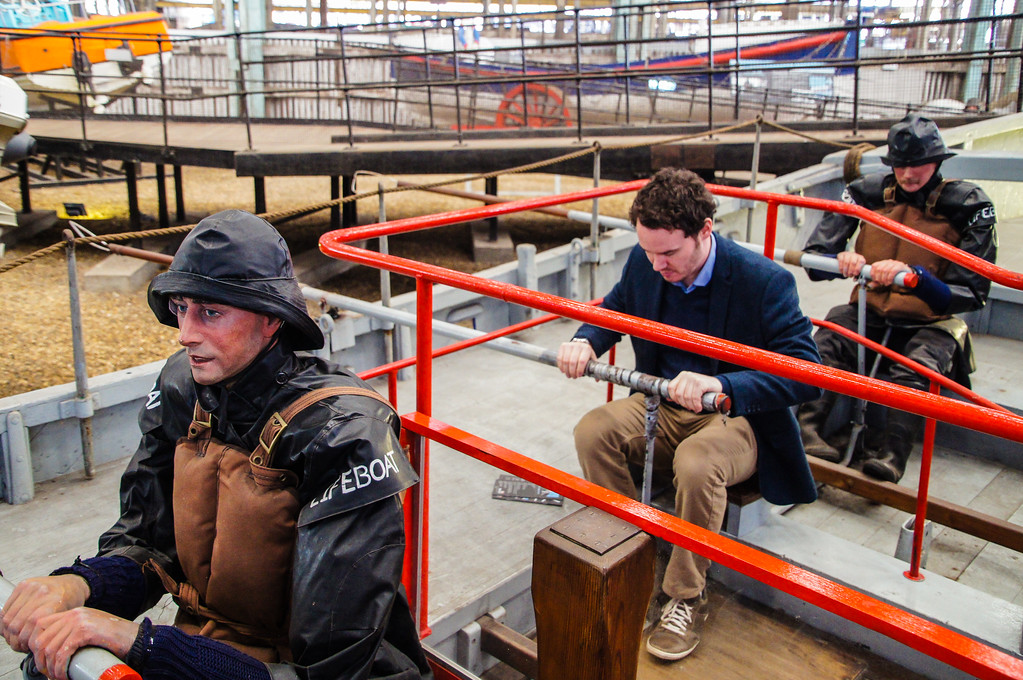 husband trying to row in the collection of life boats exhibit at the historic dockyard chatham