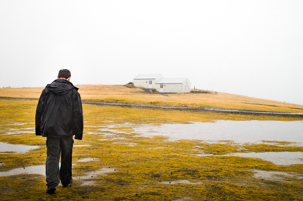 Gary walking towards the white building at Dyrhólaey