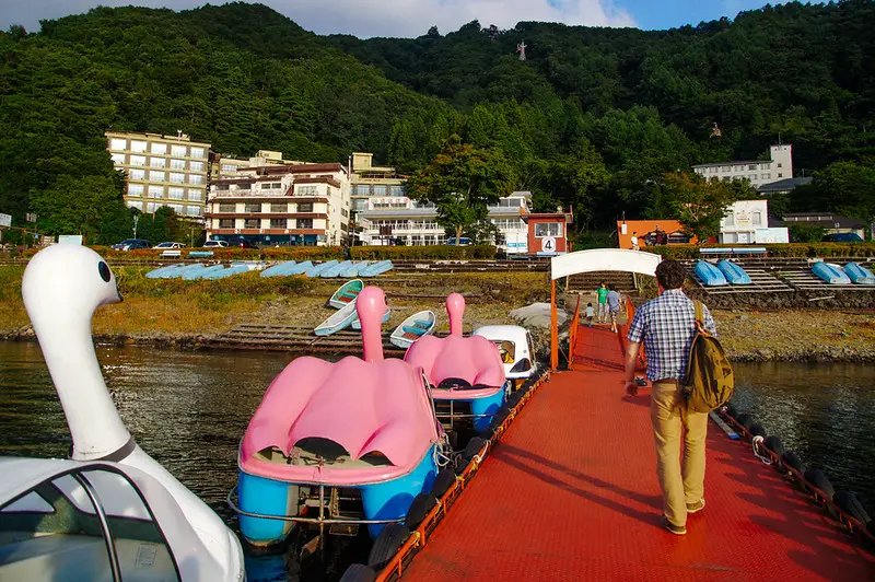 Husband walking down pier with docked swan peddle boats on lake kawaguchiko