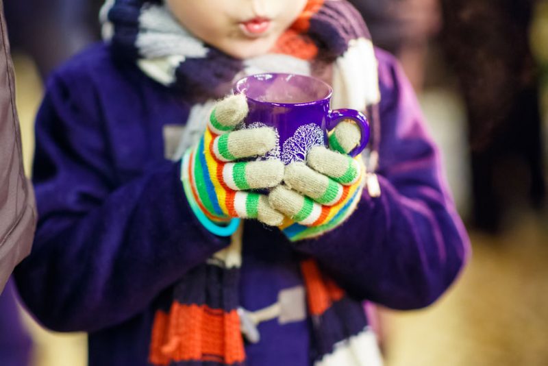 Little kid boy with hot chocolate on Christmas market