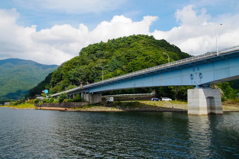 bridge across lake kawaguchiko with mountains in background