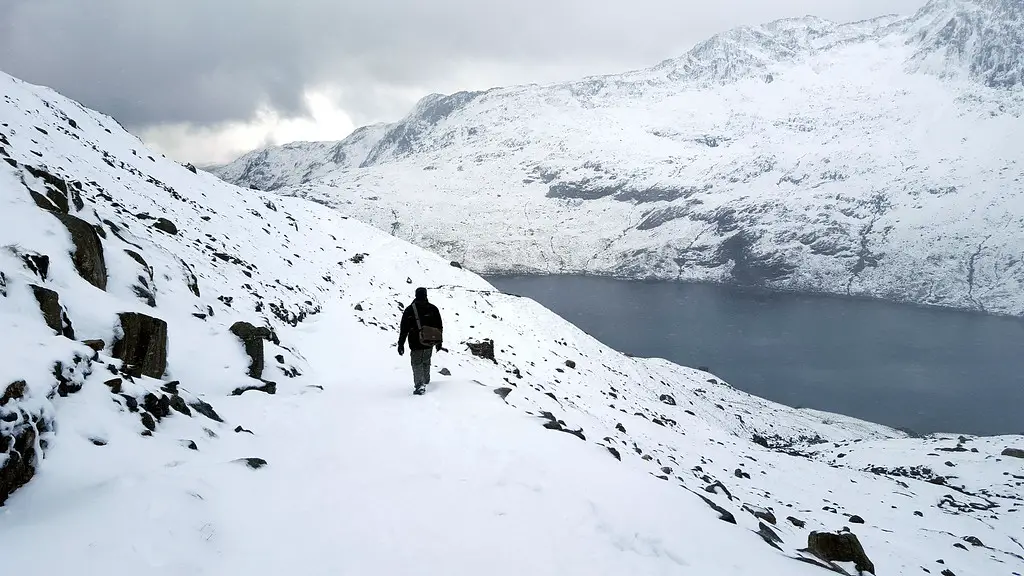 husband walking down snowy path of miners track up mount snowdon