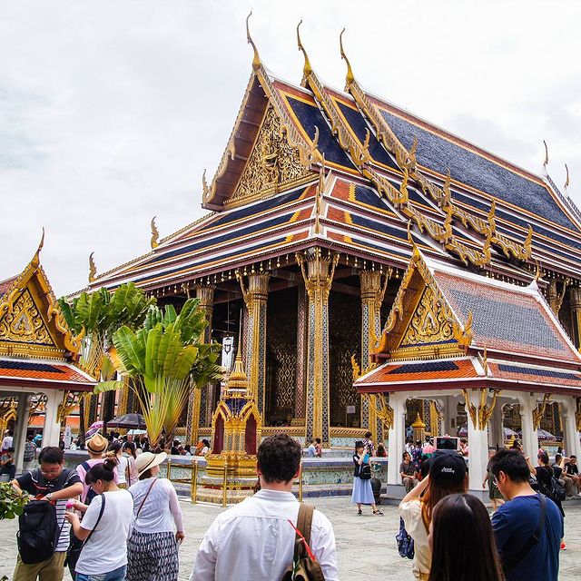 husband walking towards colourful temple in bangkok thailand