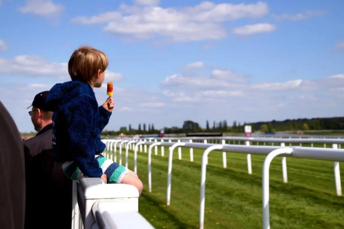 kid with ice lolly on fence at the Newbury Racecourse main field on al shaquab lockinge day