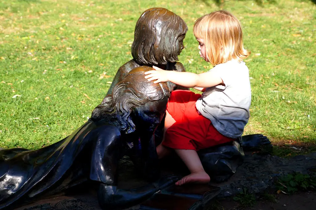 little girl embracing alice in wonderland statue in guildford