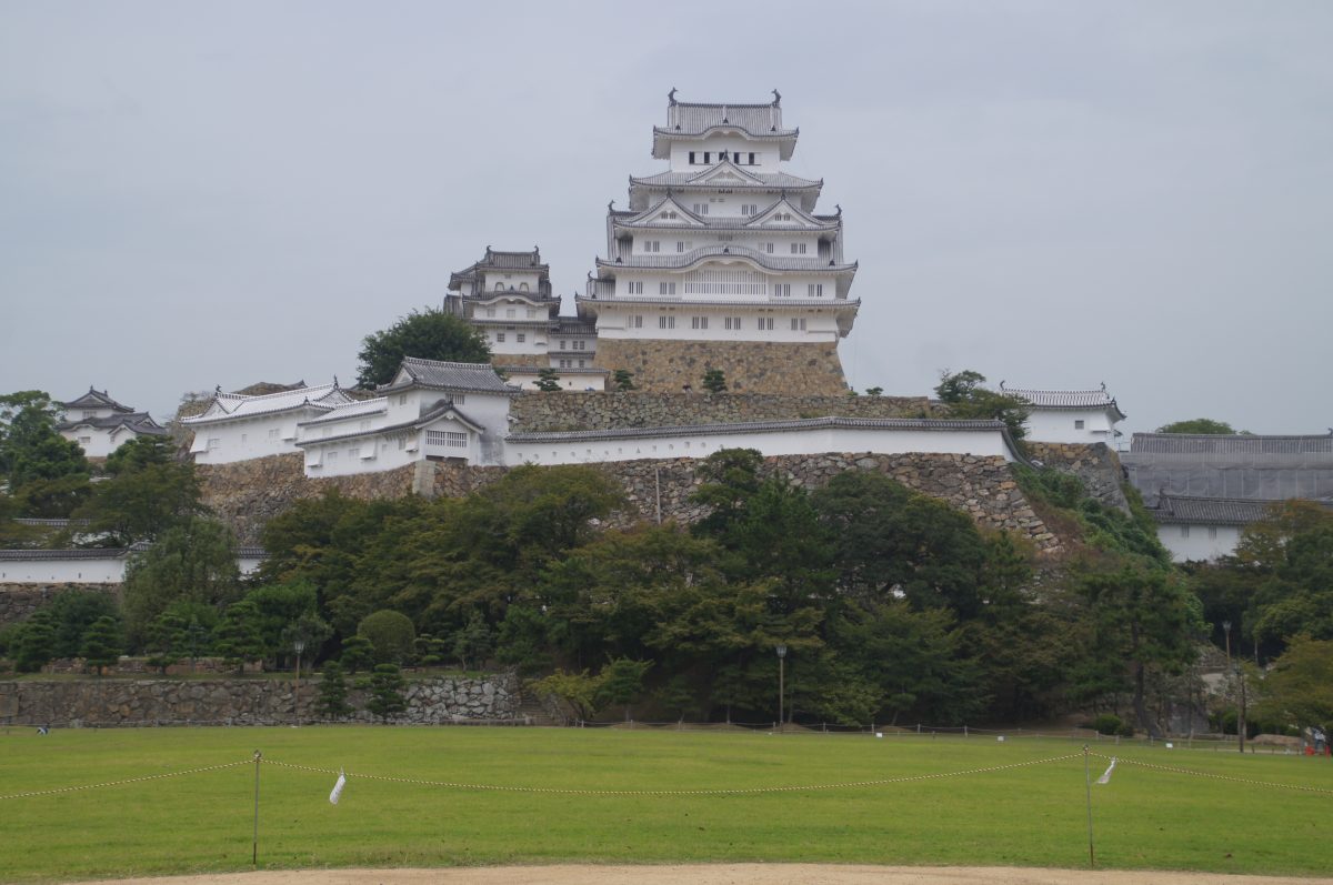Himeji Castle seen from a distance across the park on a grey day