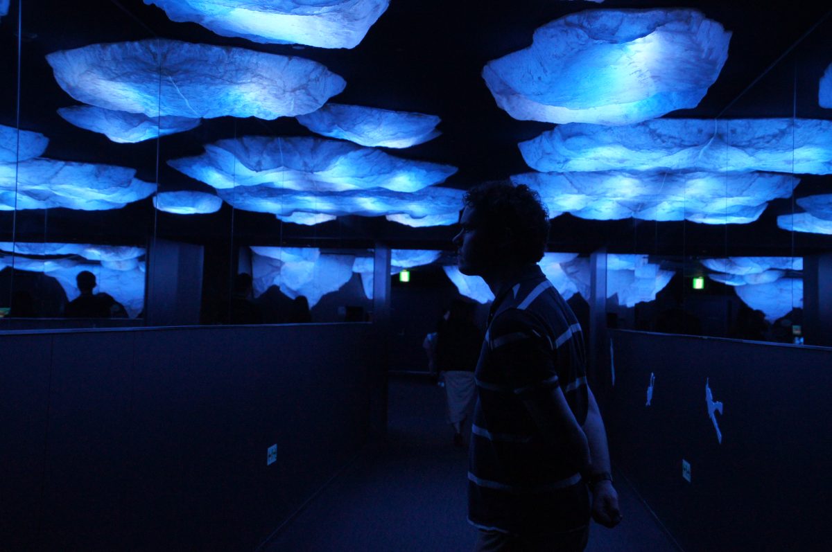 Gary silhouetted beneath blue illuminated overhead displays inside Osaka Aquarium Kaiyukan
