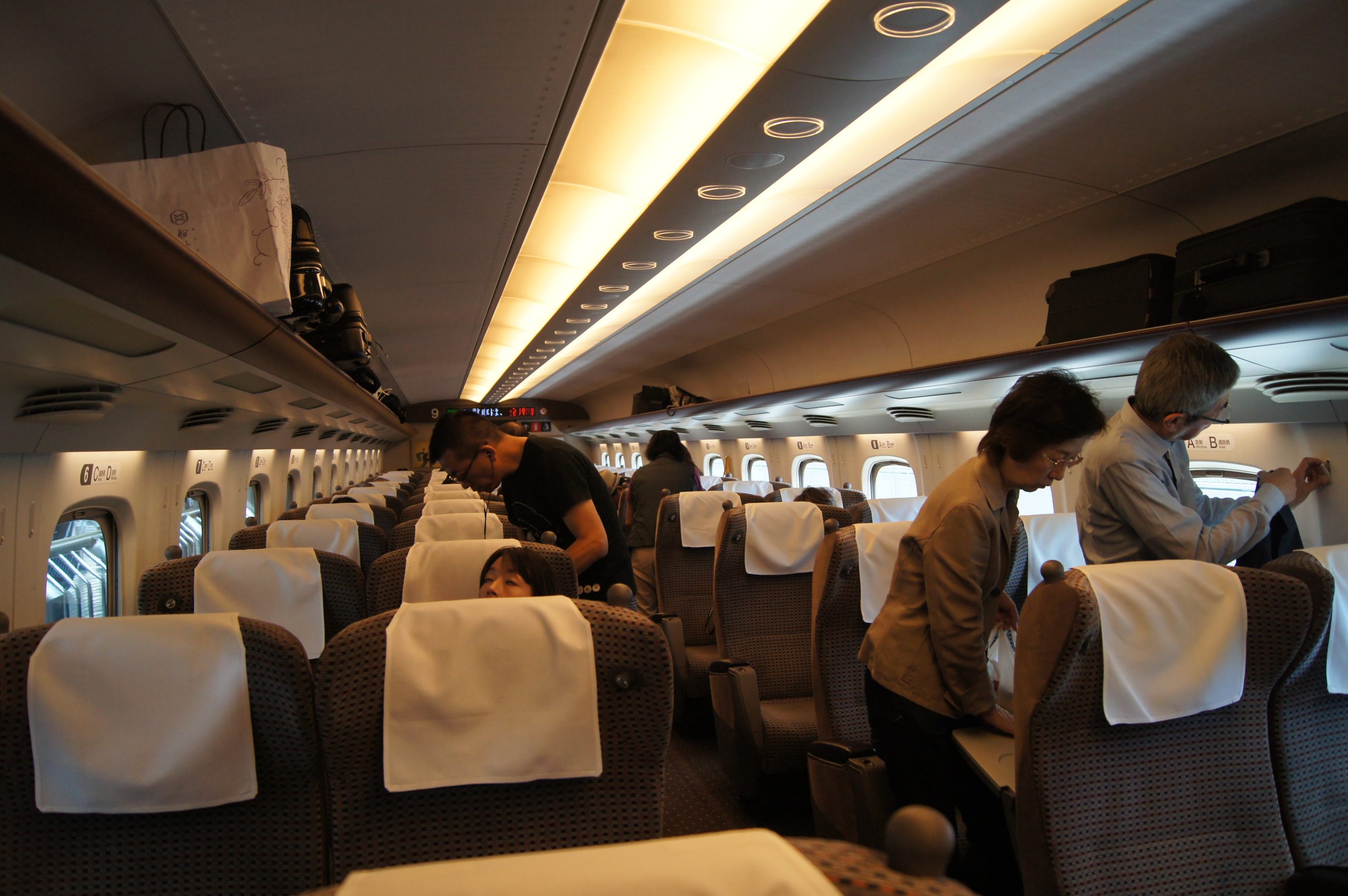 DSC06139 scaled Passengers stand in the aisle of a Japanese train carriage.