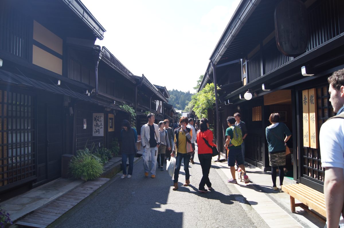 DSC06157 Visitors walk along a narrow street lined with dark wooden buildings in Takayama's old town.