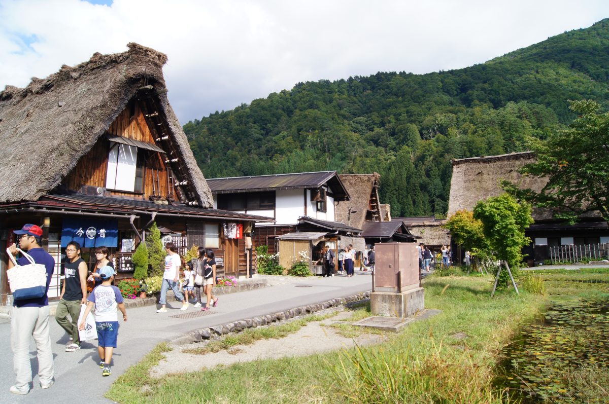 Visitors walk along a village street lined with traditional houses in Shirakawa-go.