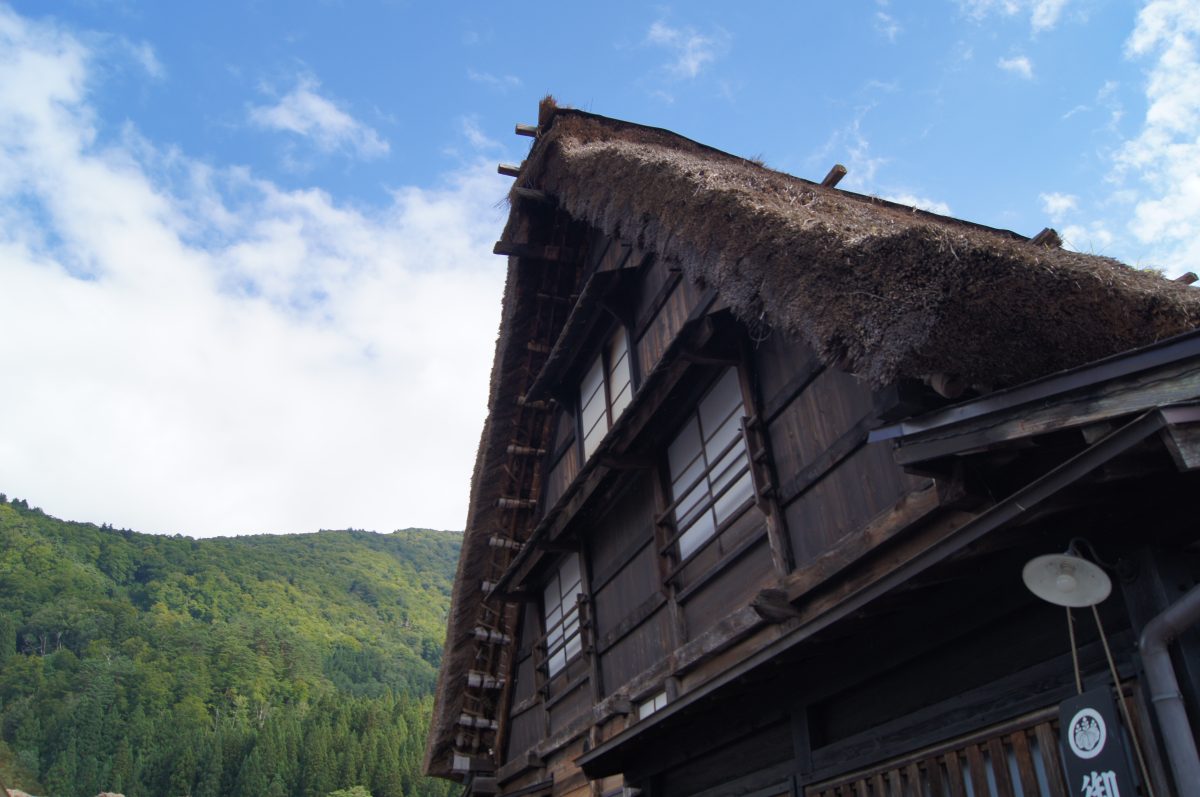 A traditional thatched farmhouse rises beneath the mountains of Shirakawa-go.