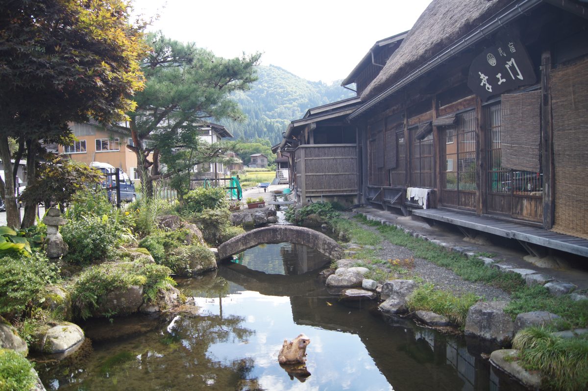 A narrow stream runs beside traditional wooden houses in Shirakawa-go.