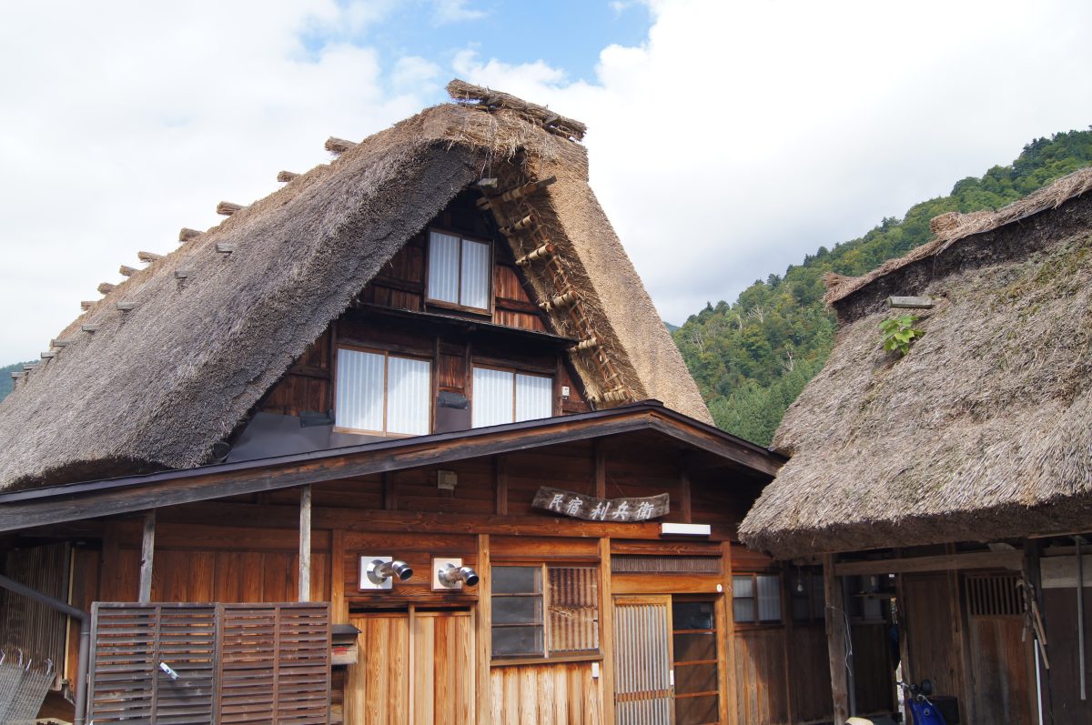 A close view of a traditional thatched farmhouse beneath the mountains of Shirakawa-go.