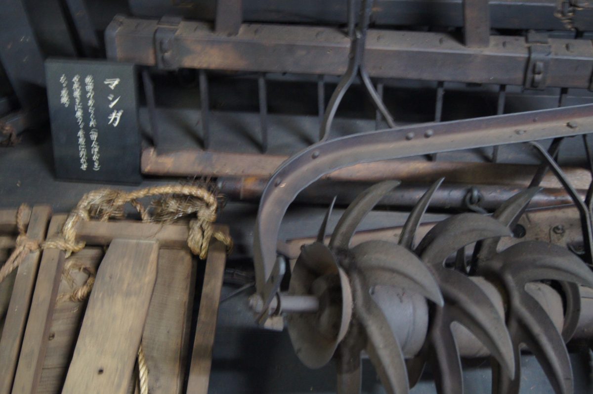 Traditional agricultural machinery and tools inside a farmhouse exhibit in Shirakawa-go.