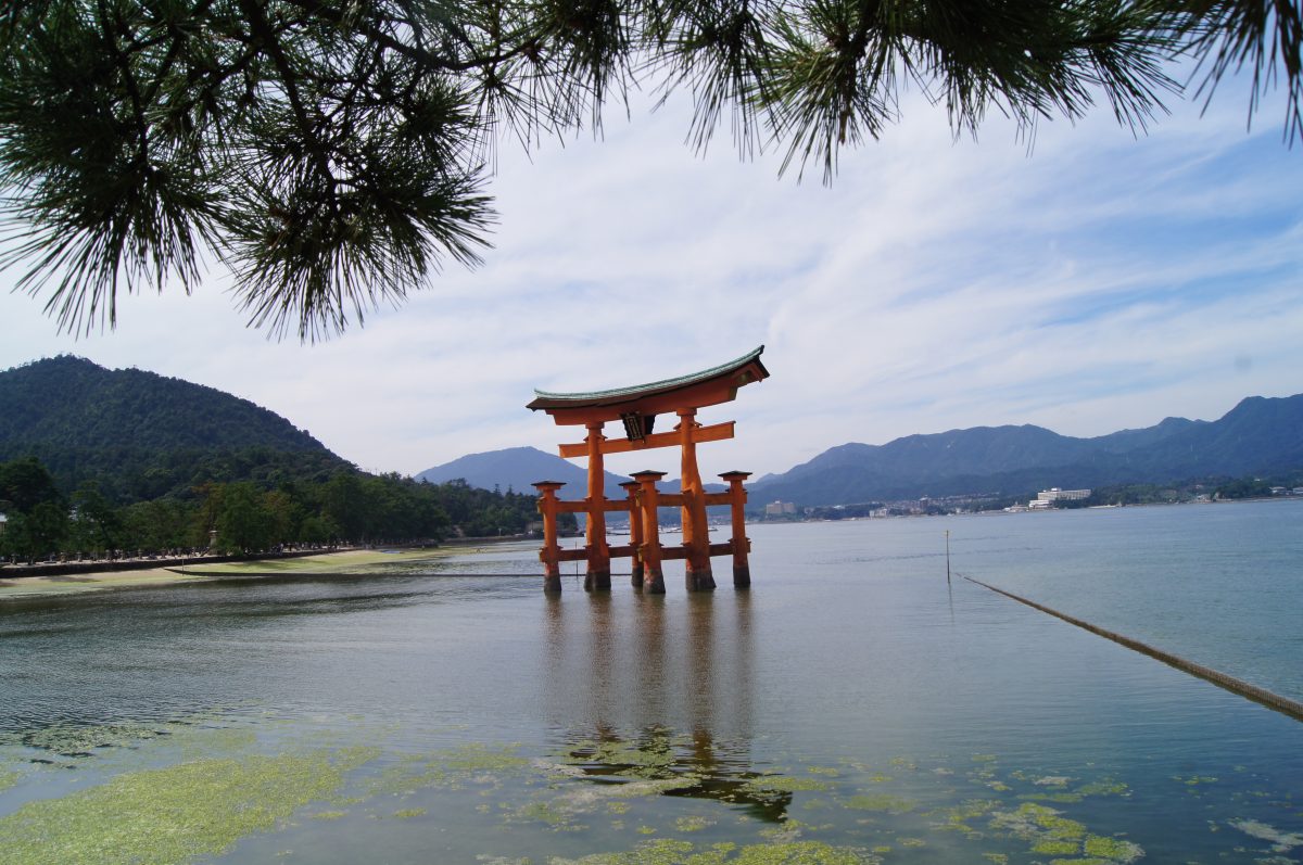 DSC06269 The great vermilion torii of Itsukushima Shrine stands in the water with wooded mountains behind it.