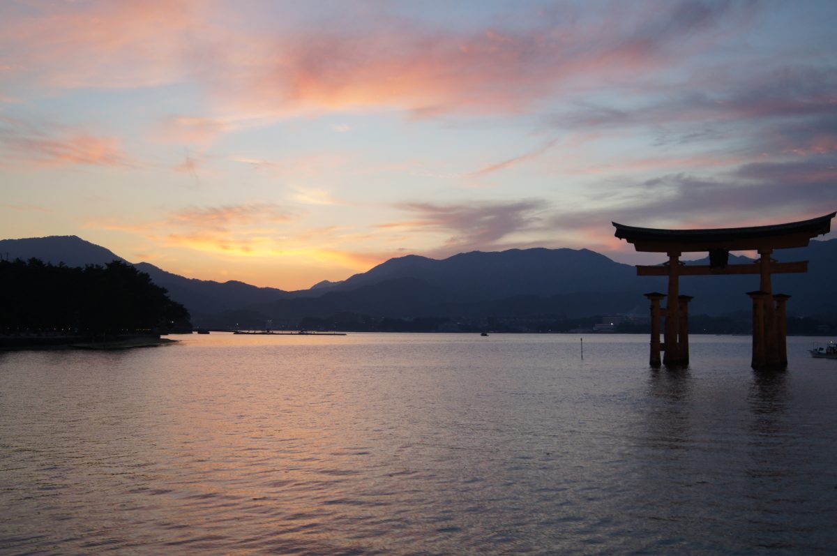 The great torii stands in the water beneath a colourful sunset over Miyajima.