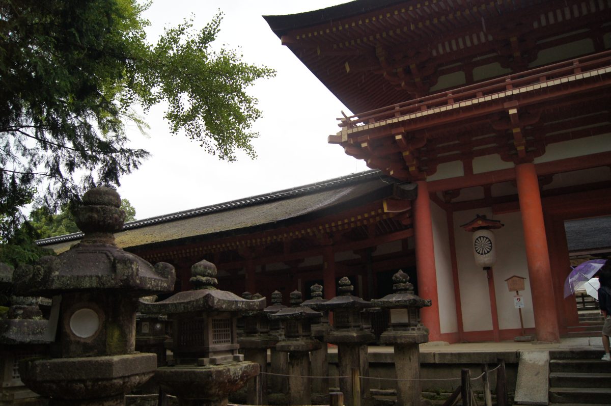 Stone lanterns beside a vermilion gate at Kasuga Taisha Shrine in Nara.