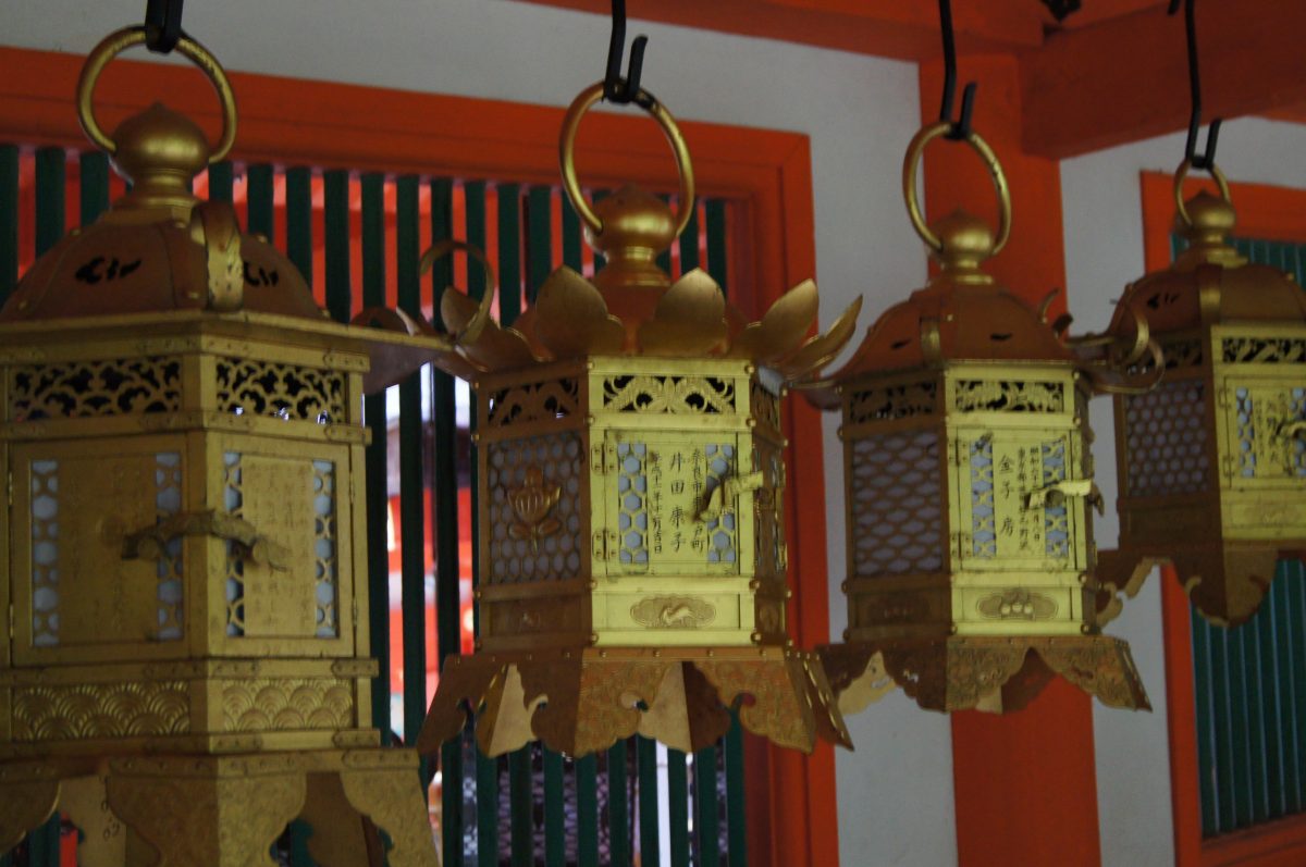 Ornate gold hanging lanterns inside the red-painted corridors of Kasuga Taisha Shrine.