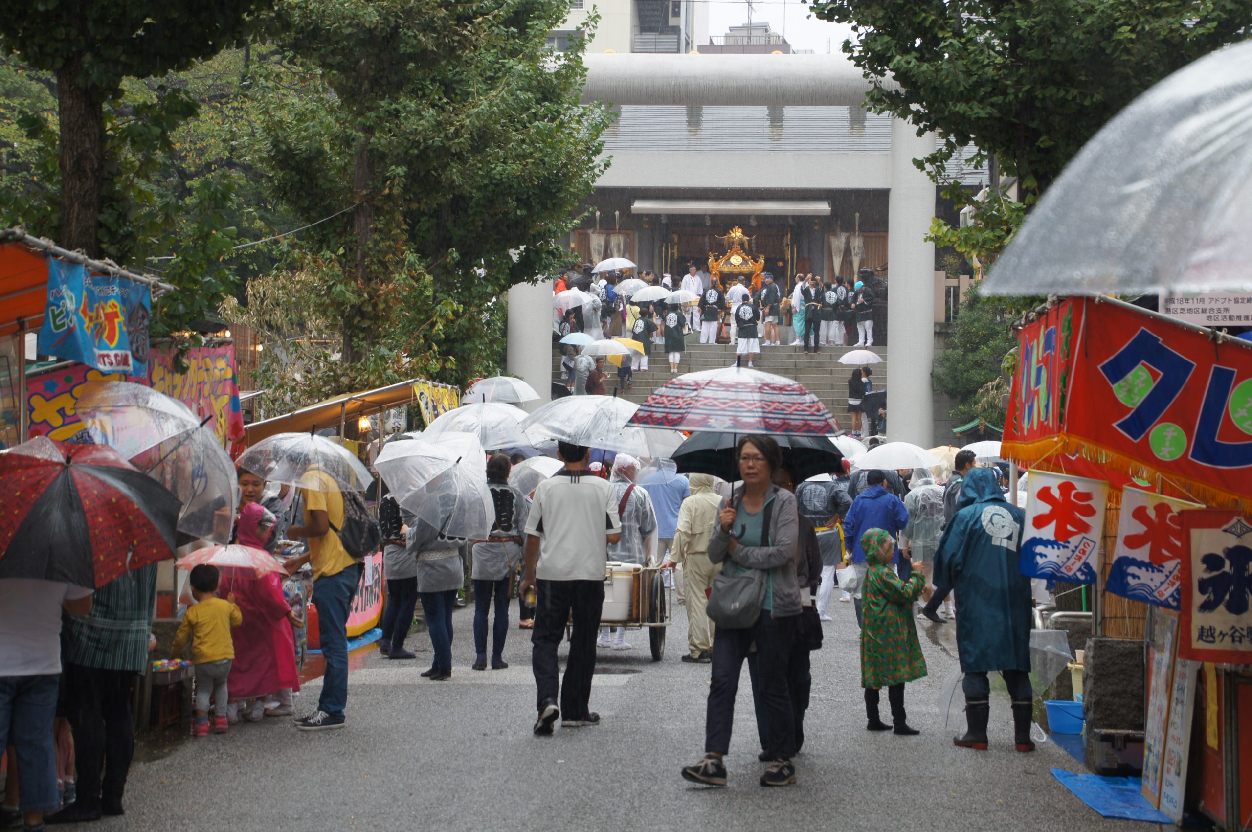 Umbrellas and festival stalls along a street during a local celebration in the rain