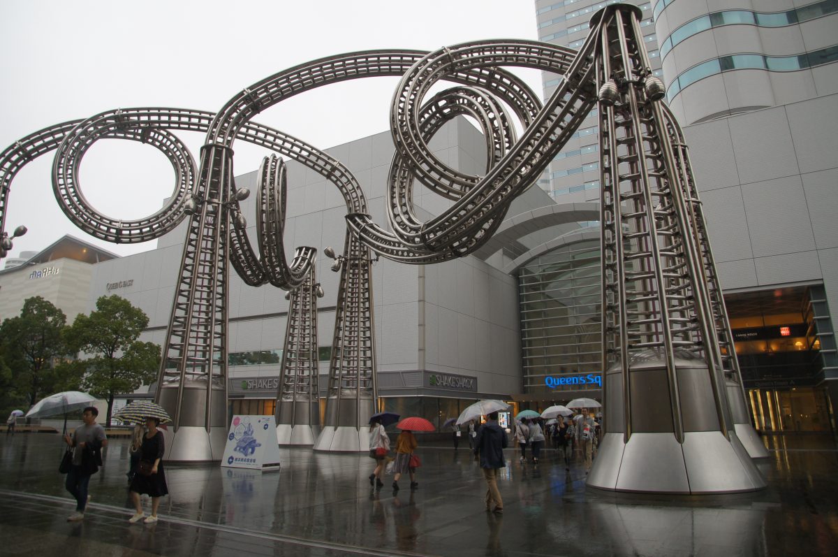 Looping roller coaster track beside modern buildings in Yokohama