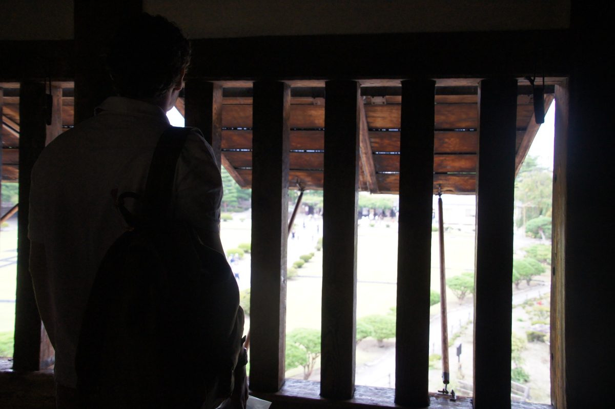 DSC09263 Visitor looking through narrow wooden openings inside Matsumoto Castle