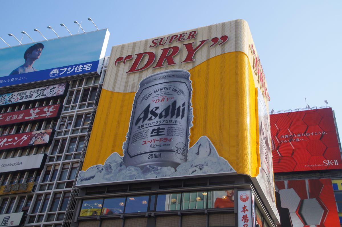 Busy Dotonbori street beneath a large Asahi beer billboard