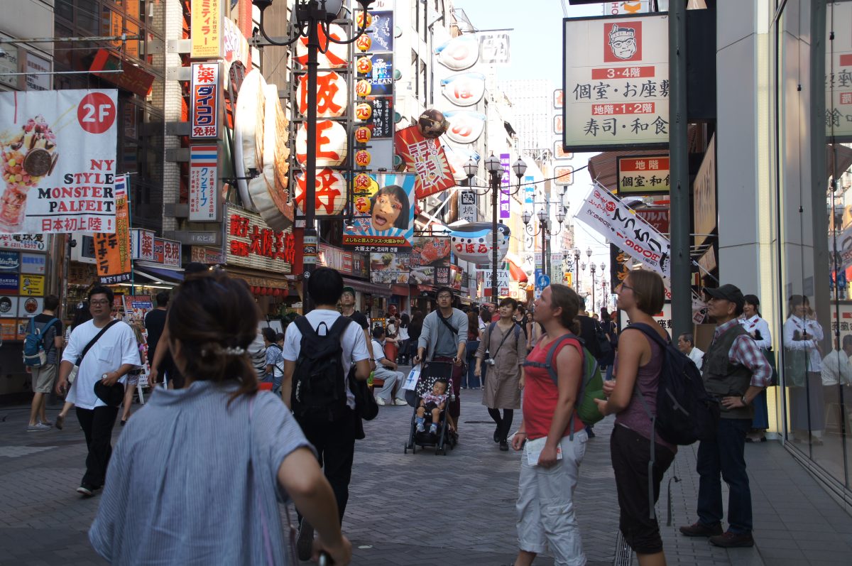 Dotonbori street lined with oversized restaurant signs beneath a clear blue sky