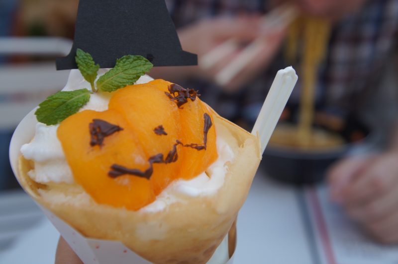 Orange pumpkin-themed dessert topped with cream, mint and a small witch hat
