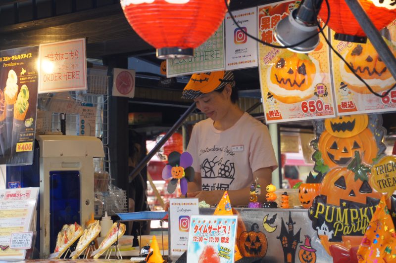 Vendor preparing desserts at a Halloween-decorated Dotonbori stall