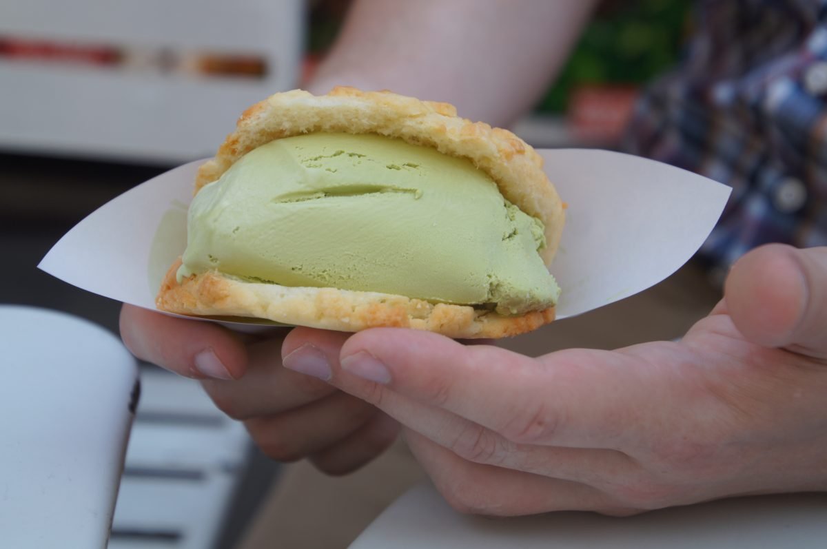 Melonpan filled with green ice cream held in a paper wrapper