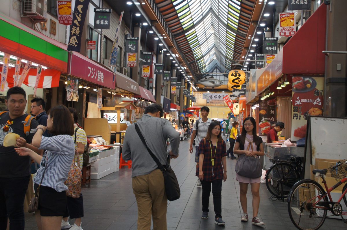 Shoppers walking along the central covered aisle at Kuromon Ichiba Market