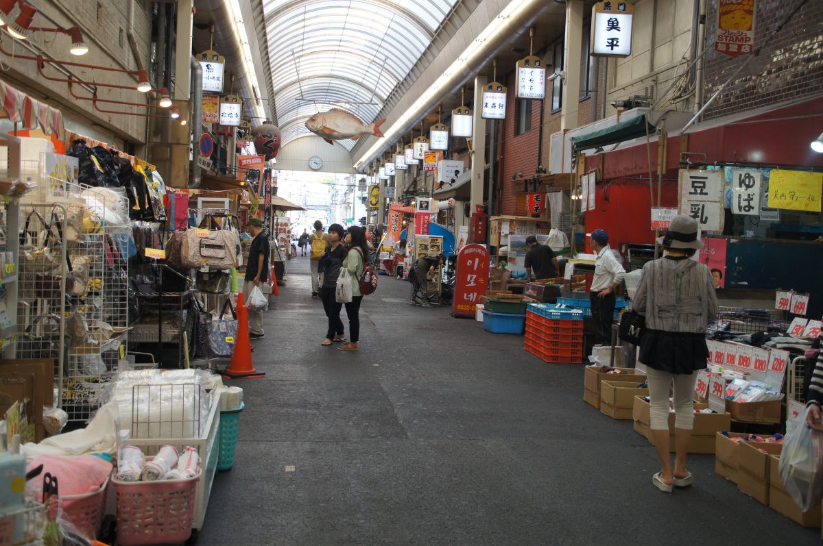 Shoppers walking past food stalls in Kuromon Ichiba Market