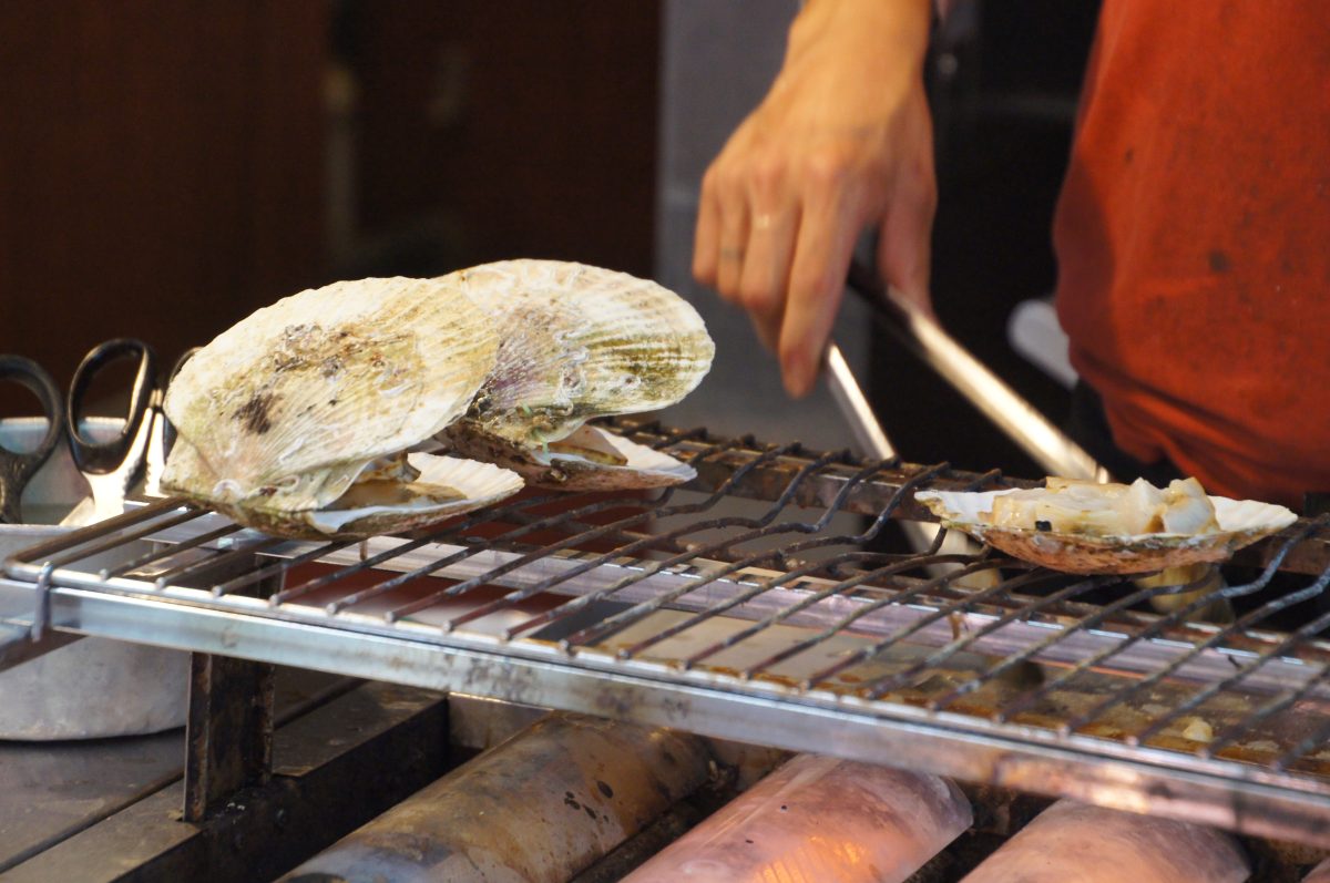 Shellfish cooking on a grill at a Kuromon Market stall