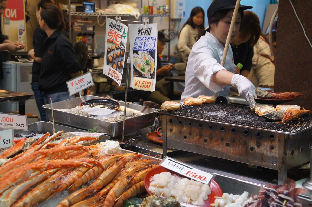 Cook preparing food on a hotplate at a Kuromon Market stall