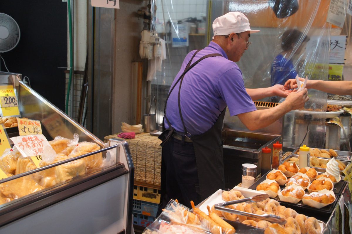 Vendor preparing food at a Kuromon Market stall