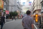 Pedestrians walking beneath shop signs in Den Den Town, Osaka