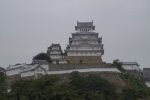 Himeji Castle keep and turrets rising above the outer walls on a cloudy day