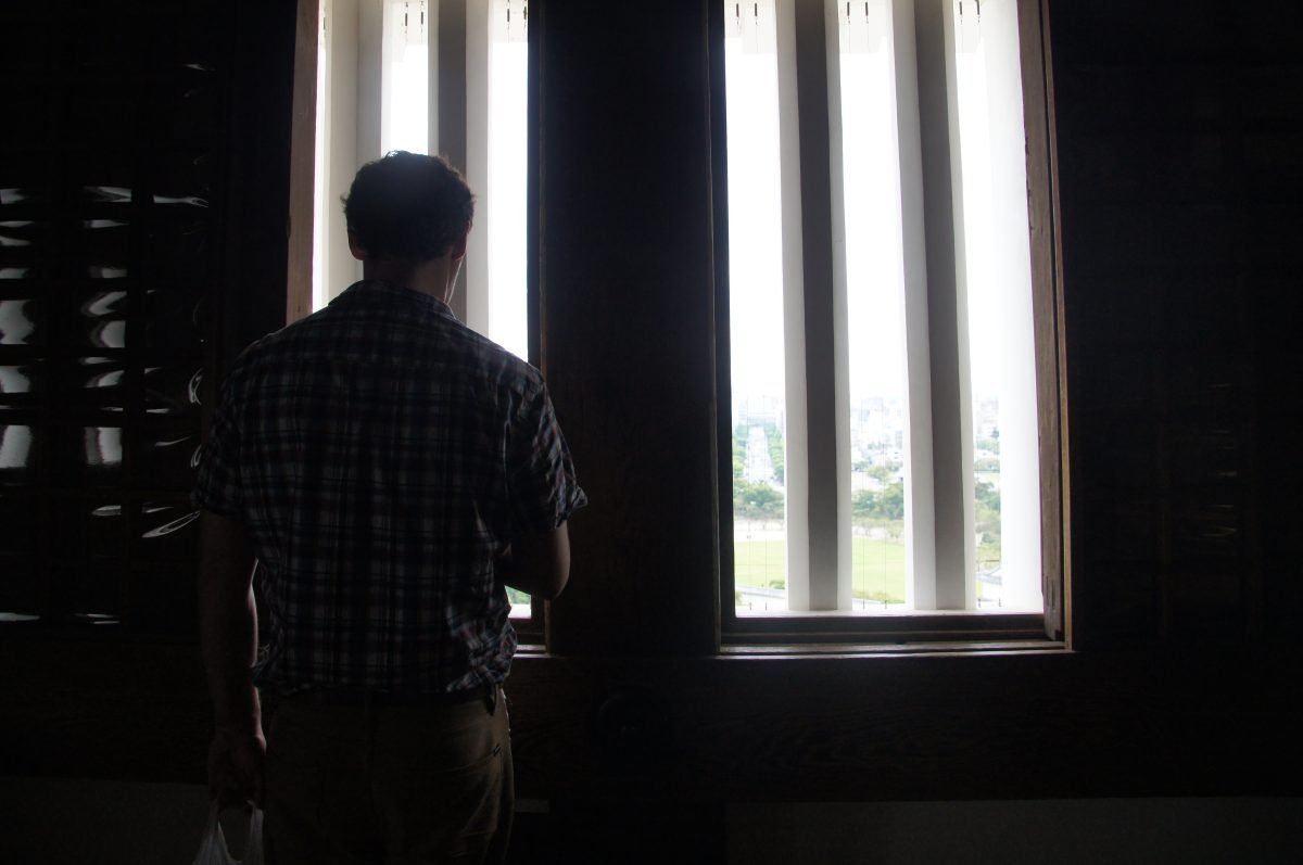 Visitor looking through a small defensive window inside Himeji Castle