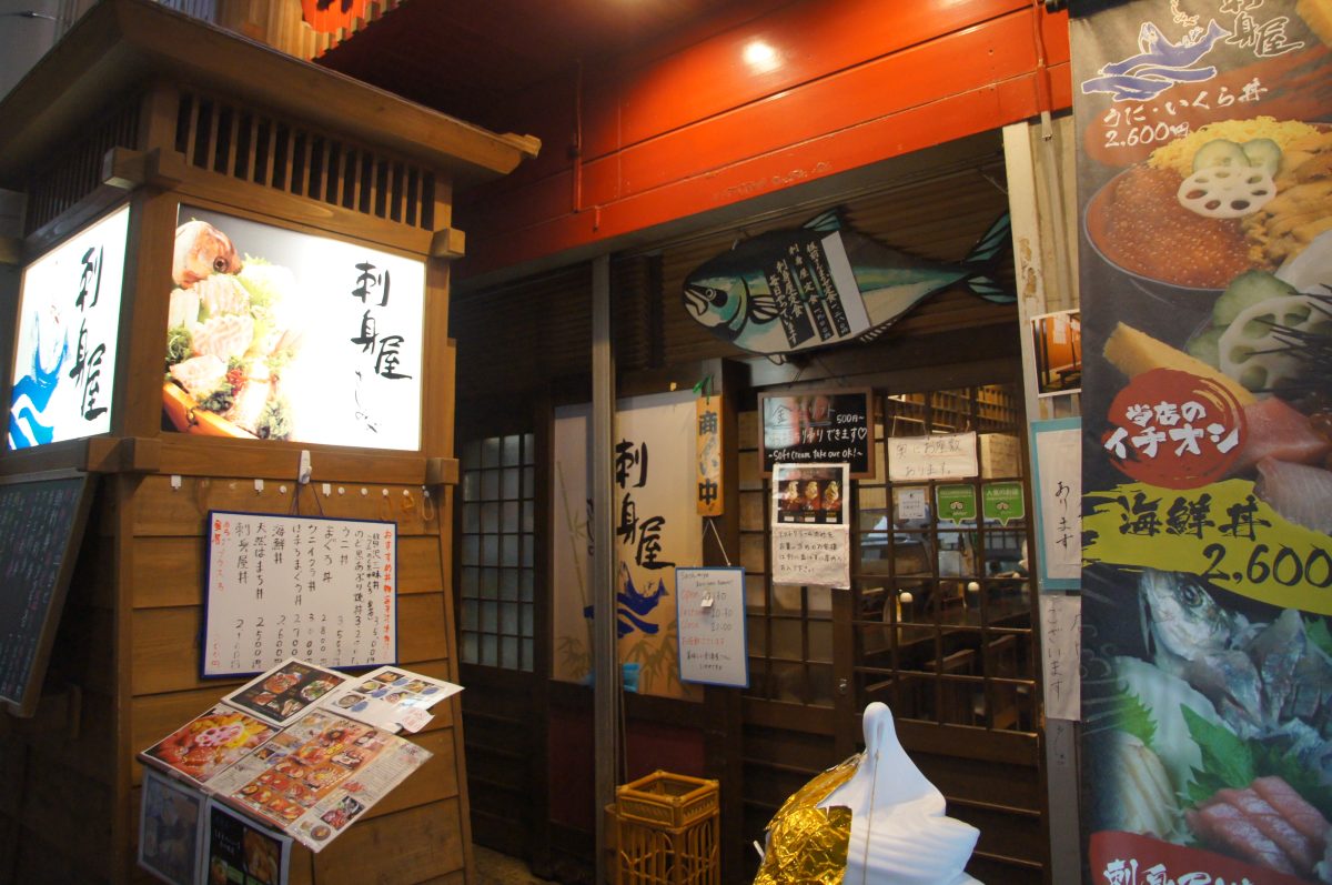 Seafood restaurant entrance and menu boards inside Omicho Market in Kanazawa