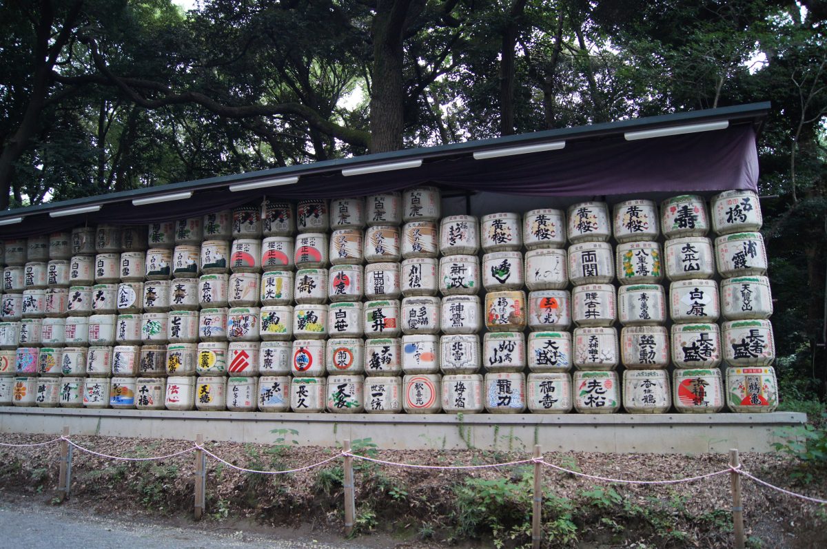 A wall of decorated sake barrels stacked along the approach to Meiji Jingu.