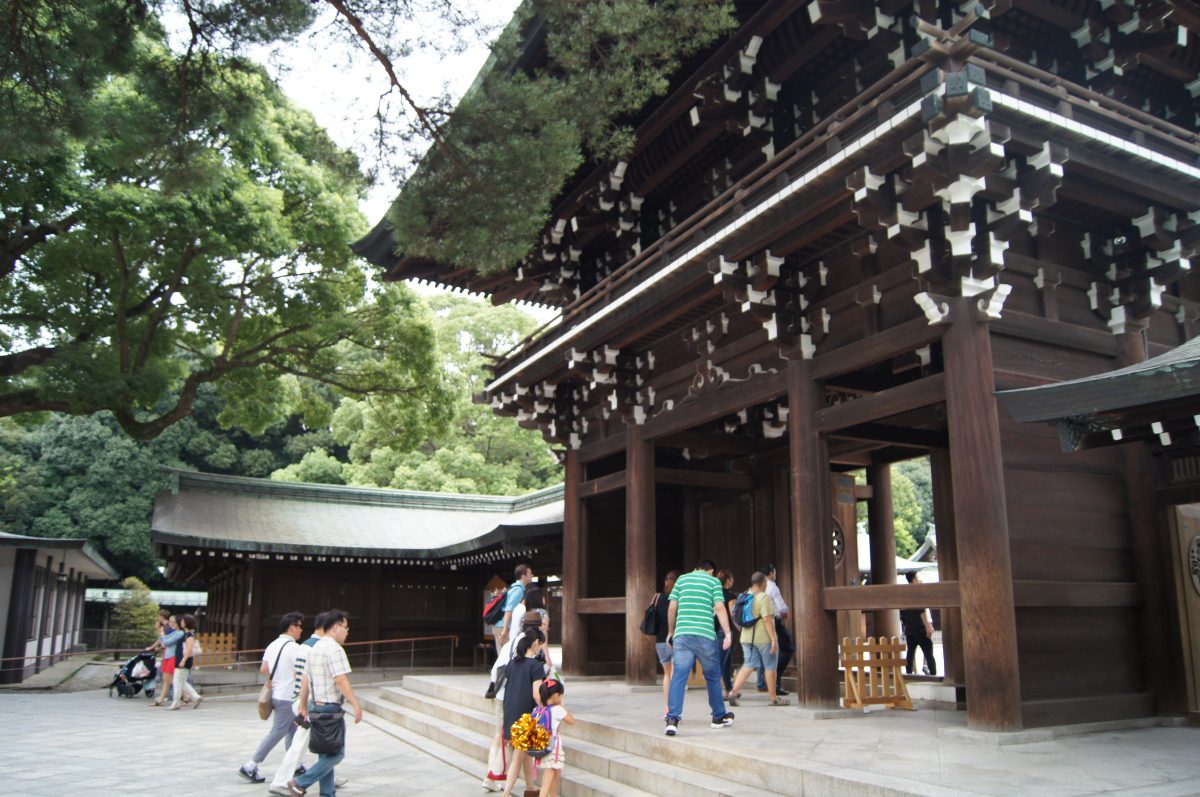 Visitors beneath the carved wooden gate at Meiji Jingu.