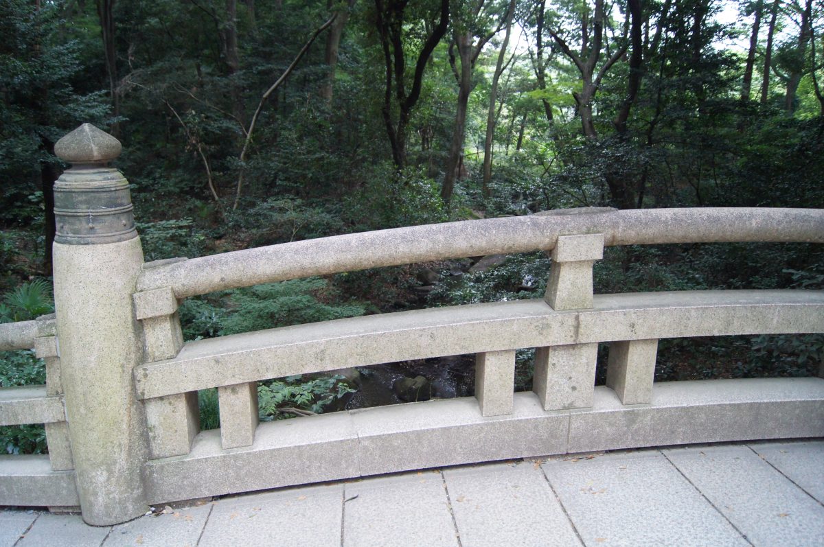 A bridge balustrade among trees along the approach at Meiji Jingu.