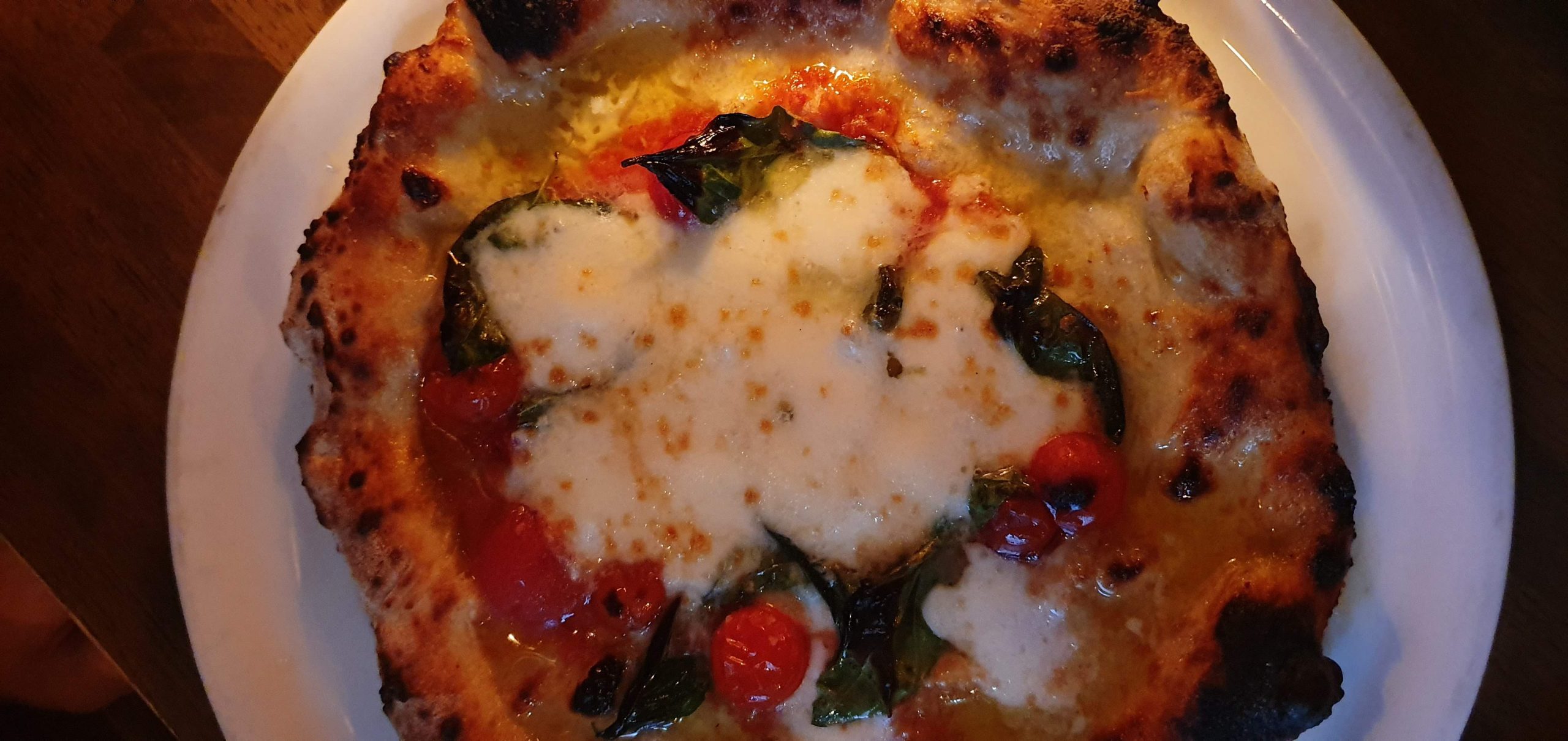 Nakameguro 38 scaled A pizza topped with melted cheese, tomato and basil at Seirinkan
