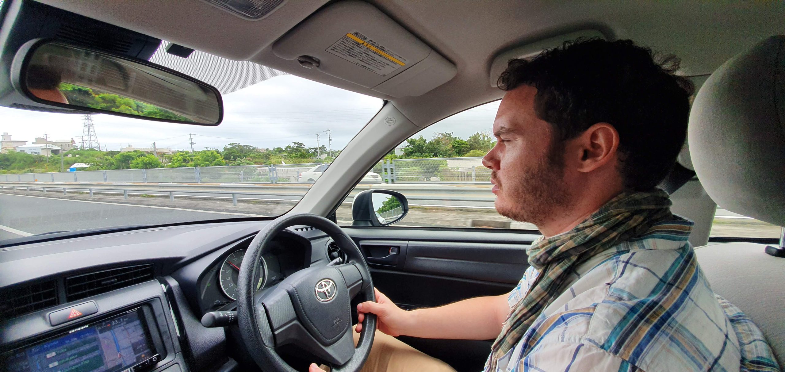 Gary driving a hire car on Okinawa Main Island with the built-in sat-nav visible.