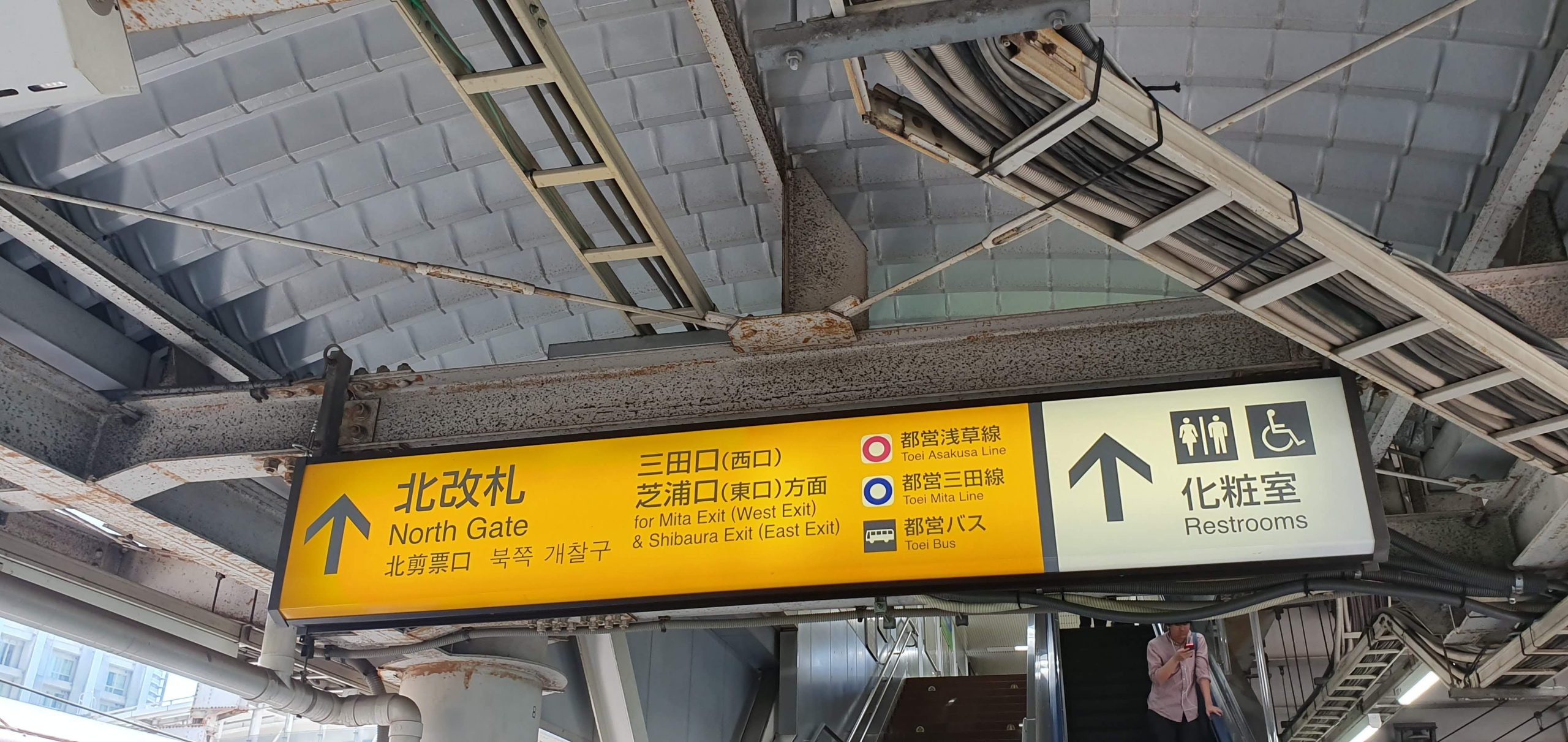 Shinjuku Station 18 scaled A yellow Tamachi Station North Gate sign points to the Mita and Shibaura exits, Toei Asakusa and Mita lines, buses and accessible facilities.