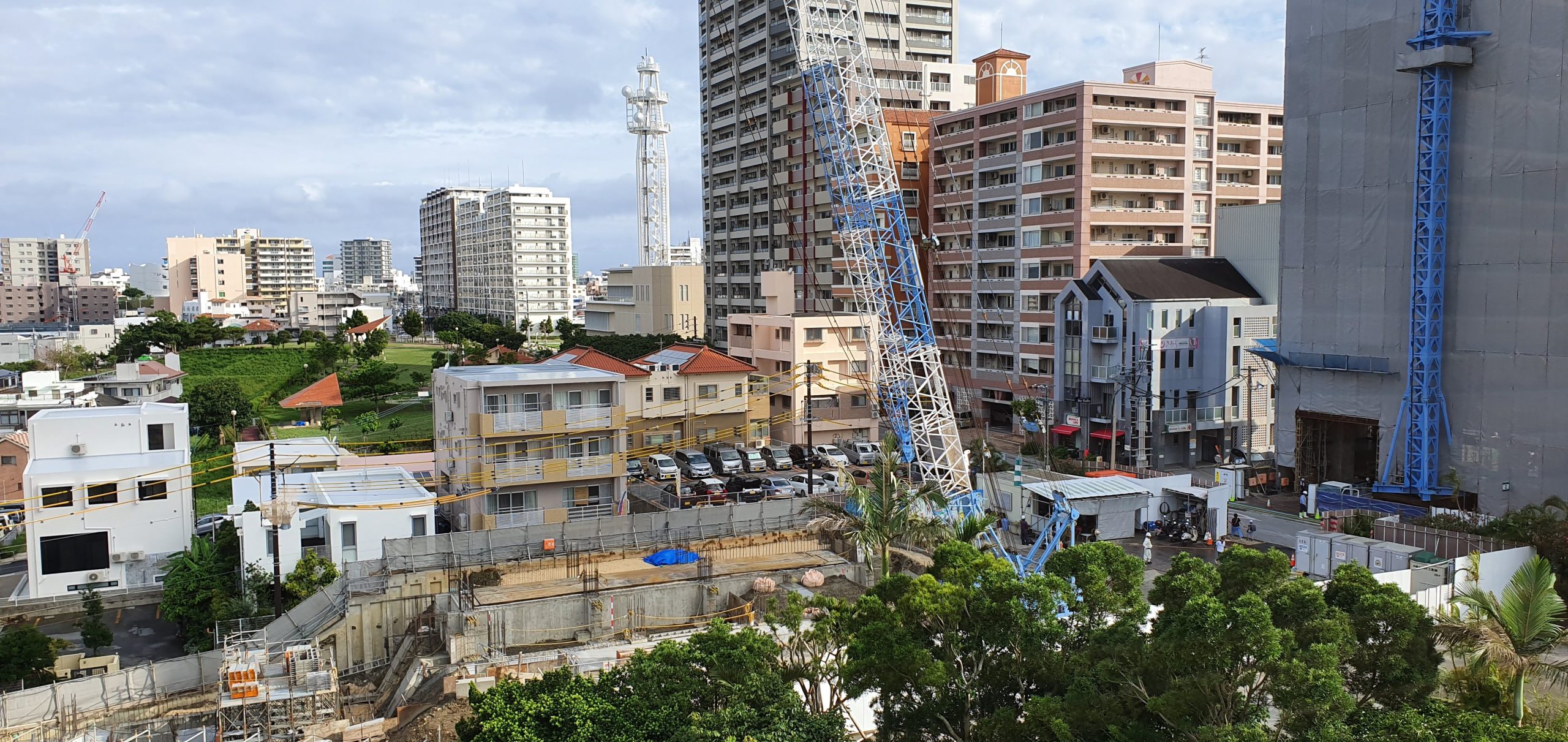 A view from The Naha Terrace looks across low-rise Naha buildings towards construction cranes and apartment towers.