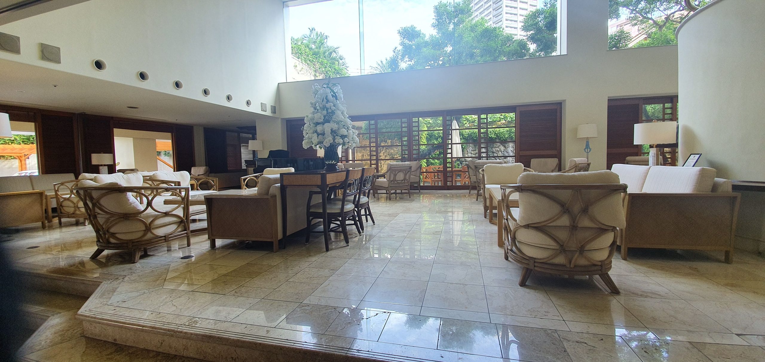 Sunlight fills the marble-floored lounge with wicker armchairs at The Naha Terrace.