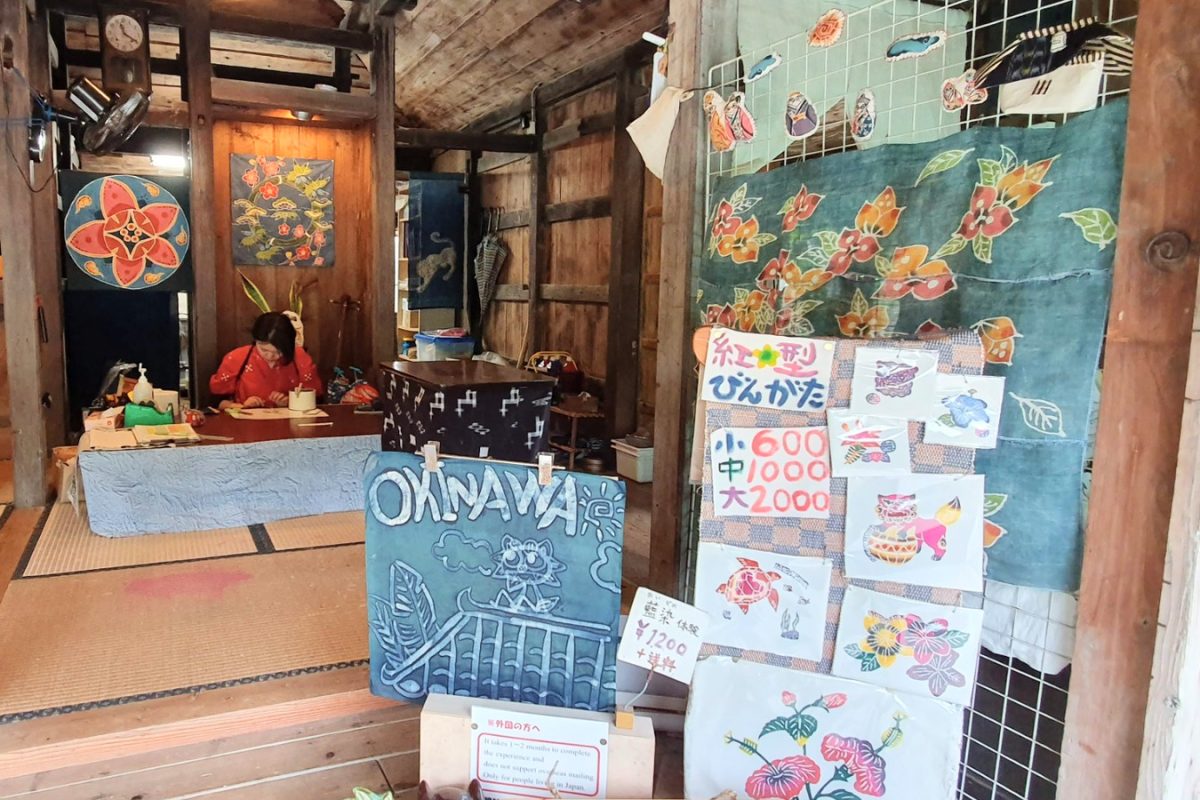 Traditional craft shop with wooden walls, painted signs and colourful fabrics.