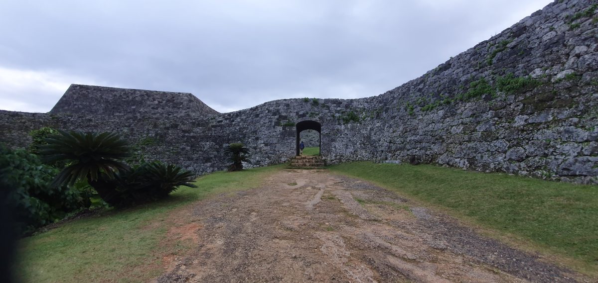 The main rounded gateway opens through the sweeping limestone walls of Zakimi Castle.